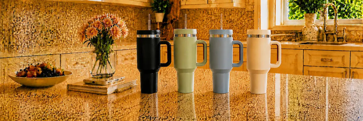 40oz insulated travel tumblers with handles and reusable straws in black, green, blue, and cream displayed in a modern kitchen setting